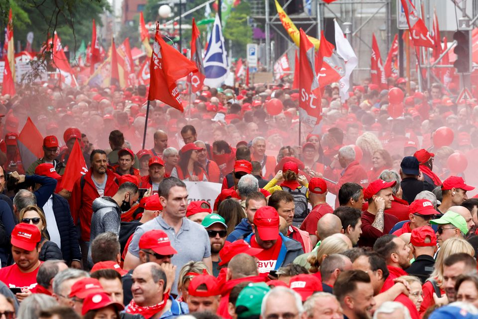 Wearing bright red caps and carrying red flags, hundreds of people march in Brussels, Belgium, against high costs of living.