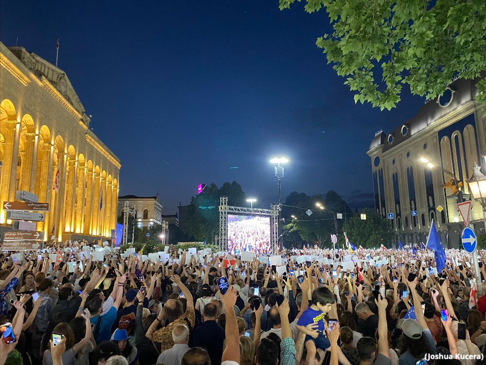 In a large square, thousands of Georgian citizens hold up placards and cell phones as they sing Ode To Joy during a demonstration in favor of joining the European Union.