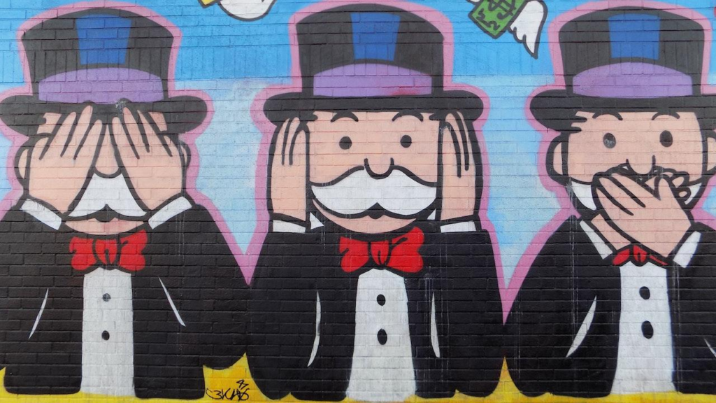 A street mural shows the iconic Monopoly Man in the "see no evil, hear no evil, speak no evil" poses.