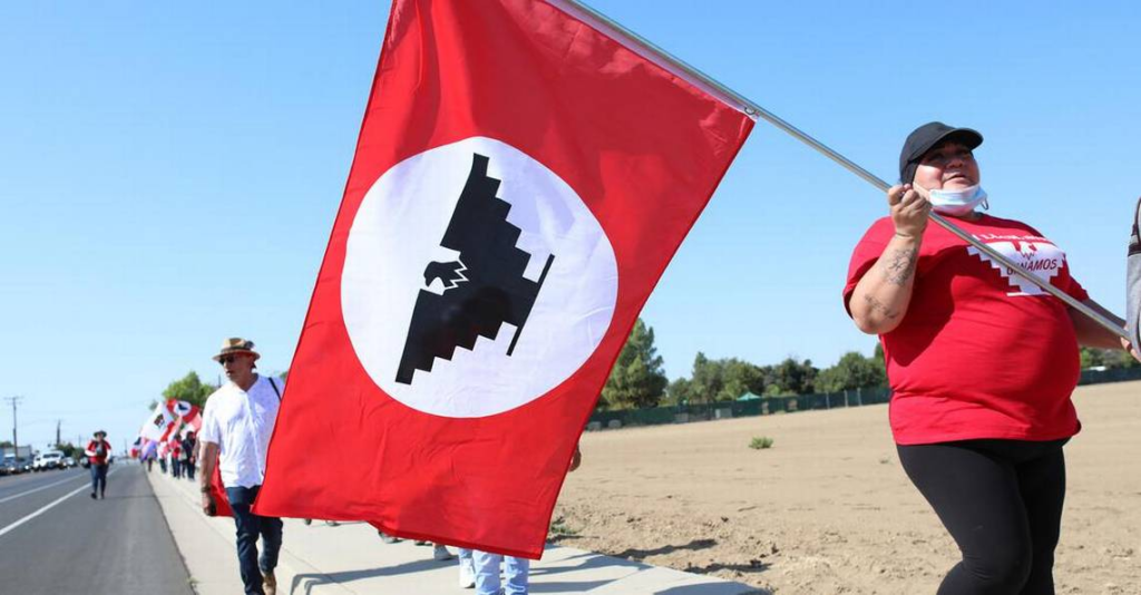 Carrying the iconic red, white, and black United Farmworkers flag, farmworkers march for the governor's signature on a bill on union voting.