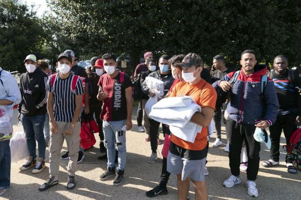 A group of migrant men where face masks and hold blankets handed out to them by mutual aid groups in Washington, DC.