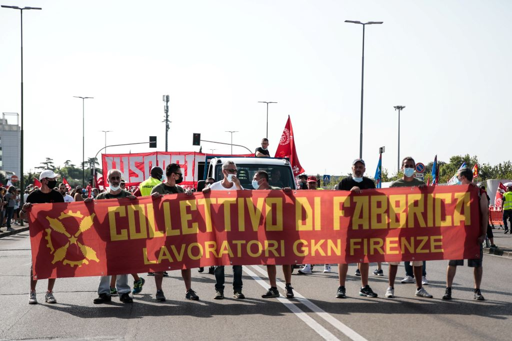Italian auto workers hold a red and yellow banner during a strike.