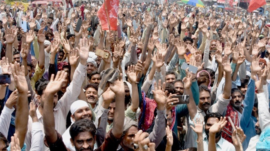 A tight-packed crowd lifts hands in the air to celebrate a victory for powerloom workers in Pakistan.