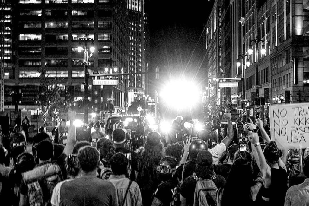 Racial justice protesters face a row of riot police at night in Detroit, 2020. Photo by Anna Van Schaap.