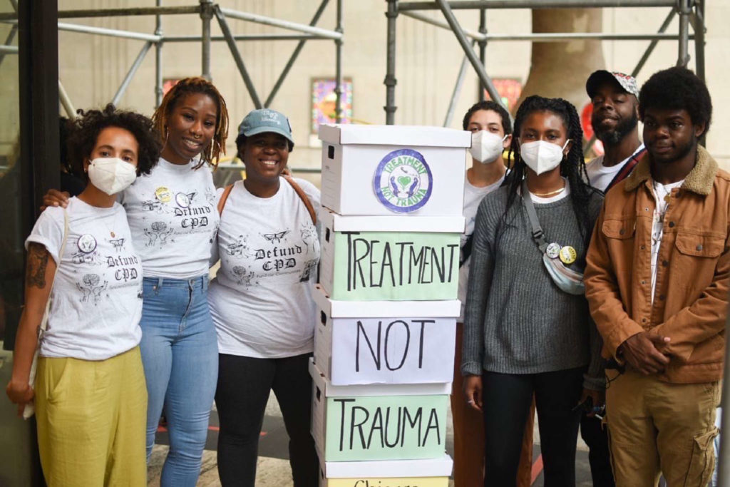 A group of Black organizers in Chicago, IL, submit boxes of petitions with signs on the sides that read "Treatment Not Trauma". The petition calls for removing police from mental health crisis response teams.