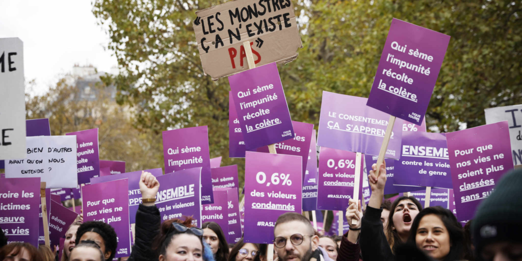 Dozens of purple signs protesting gender-based violence are held aloft by women demonstrators in France.