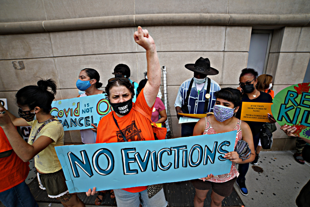 Tenants in New York City hold signs  as they rally against eviction.