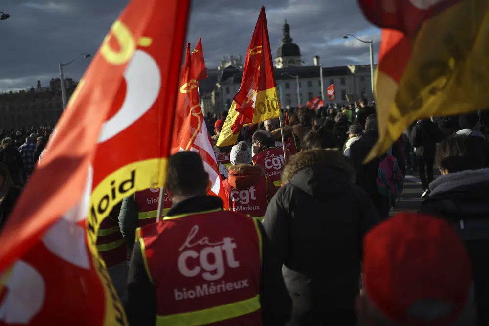 Union members in red vests and colorful flags join a demonstration during France's strike against the government's threat to raise the pension age.