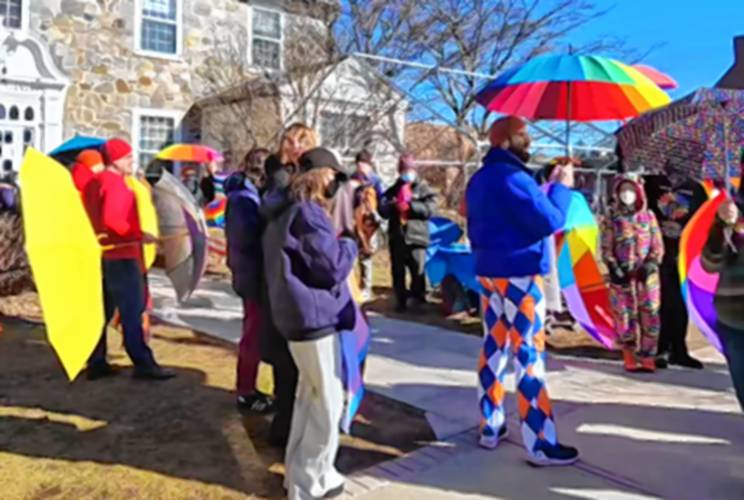 LGBTQ allies and supporters hold rainbow parasols to provide protective support during the local library's Drag Queen Story Hour.