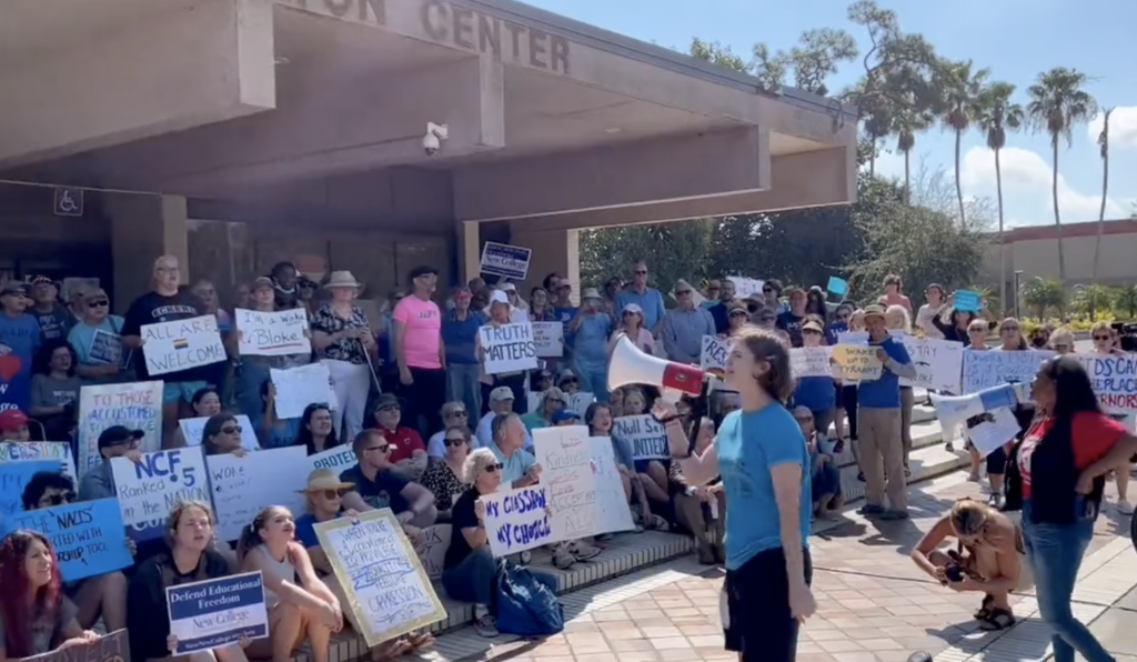 A pair of students speak into megaphones to a group of demonstrators opposing Florida's right-wing assault on education.