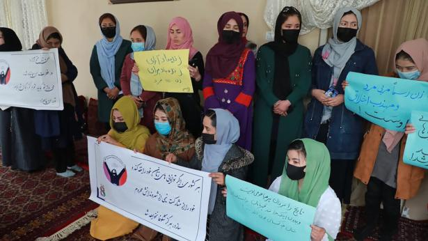 Wearing colorful dresses and hijabs along with face masks to prevent covid, a group of Afghan women hold signs on International Women's Day.