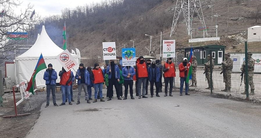 A row of protesters wear red vests and blue jackets as they picket outside a mining site in Azerbaijan.