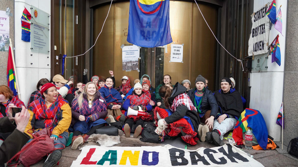 A group of Sami Indigenous protesters sit in front of the doors of the Norwegian Energy Office opposing an illegal wind farm. 