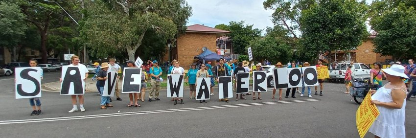 Holding signs that spell out "save waterloo", housing justice protesters rally to save public housing in Australia.