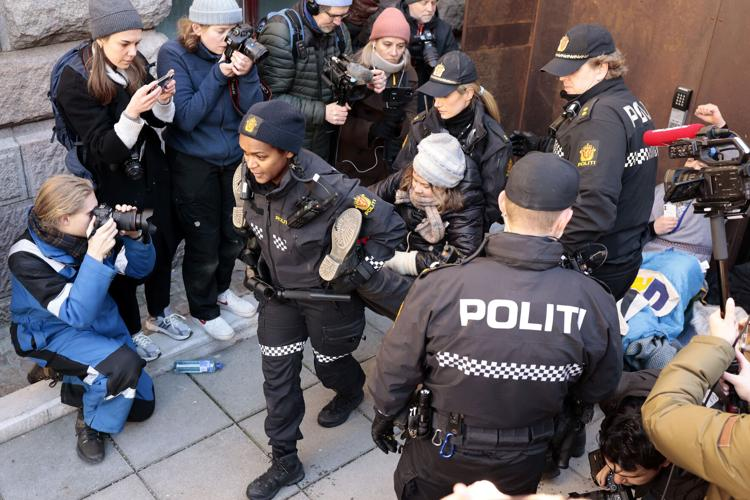 Two police officers carry away climate activist Greta Thunberg during a protest outside the Norwegian Energy Minister's office.