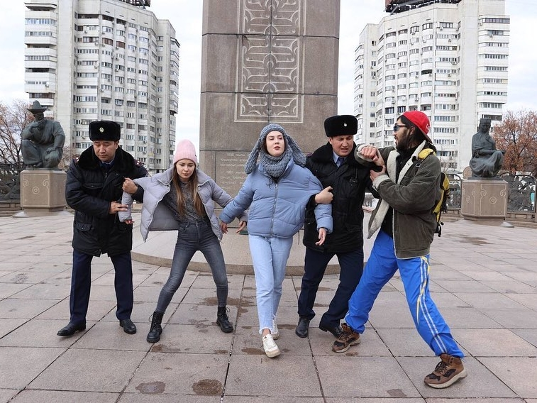 Bundled for cold weather, three activists in Kazakhstan struggle as two black-clad police officers try to arrest them for a political protest.